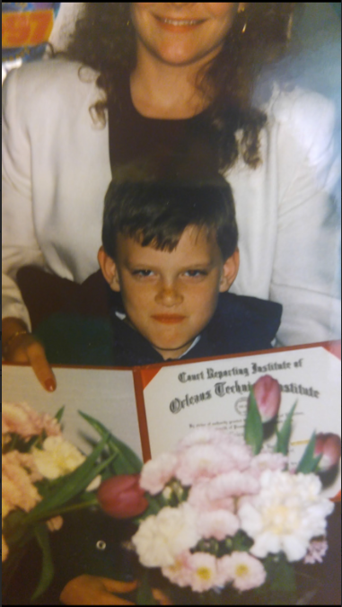 Mike as a child beside his mother, holding her court-reporting diploma among graduation flowers in 1996. The original photograph crops the top of her face.